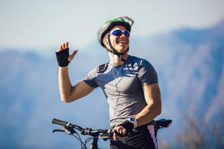 portrait of mountain biker with helmet and sunglasses listening to music and smiling.