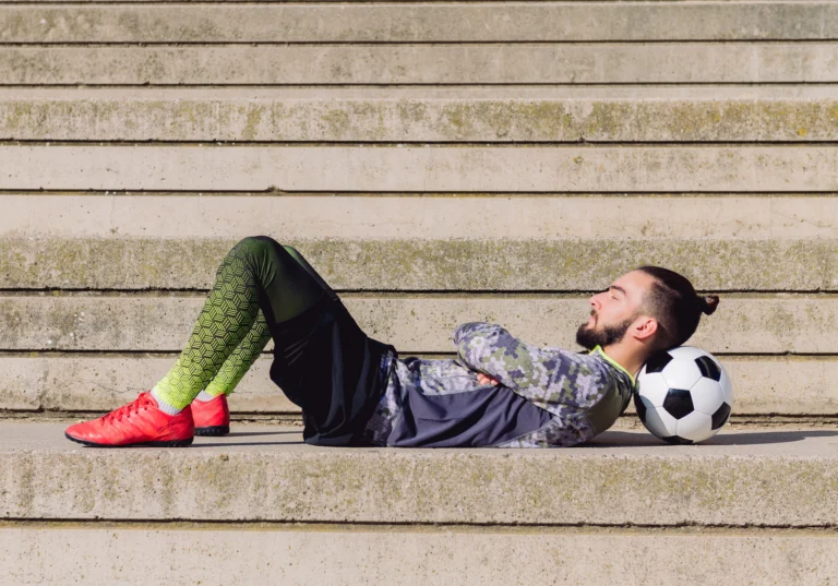 sportsman lying in a concrete soccer court